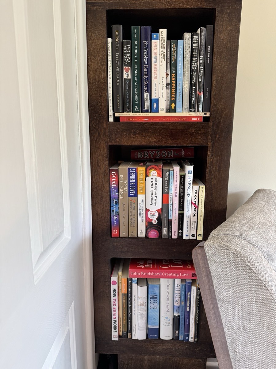 An office bookshelf of behavioural, therapeutic and leadership titles, with Mind the Gap among them.